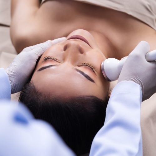 young woman receiving ultrasound facial beauty treatment skin care